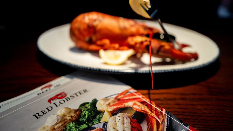 a red lobster menu in front of a whole lobster on a plate