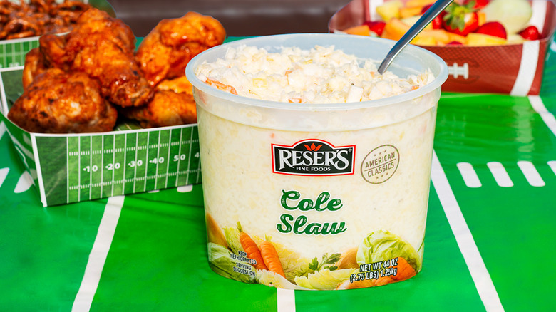 Reser's Cole Slaw sitting on a table with an assortment of snacks.