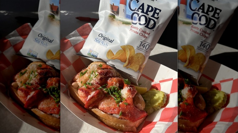 A lobster roll sits on a paper wrapper at Quincy's Original Lobster Rolls with chips