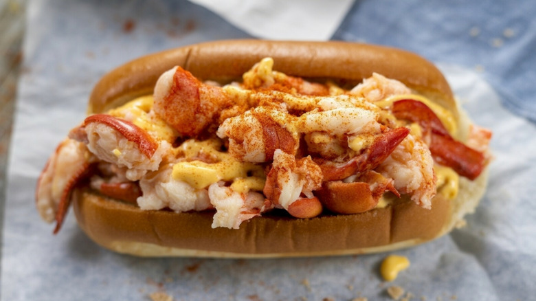 A lobster roll with sauce on a toasted bun sits on a paper wrapper