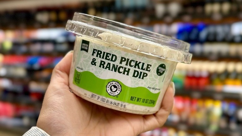 hand holding jar of fried pickle and ranch dip