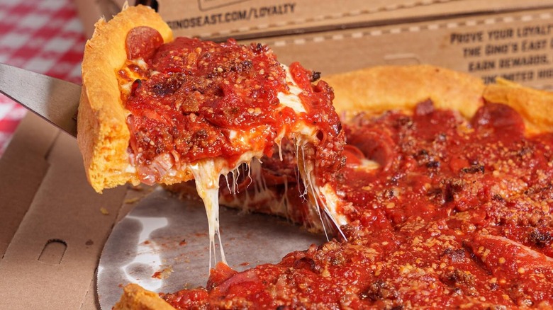 Someone serves a slice of Gino's East traditional Chicago-style deep dish pizza