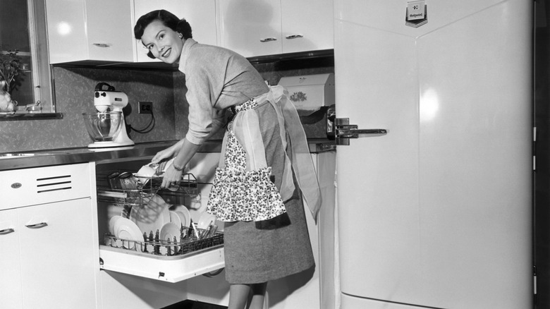 1950s housewife loading a built-in dishwasher