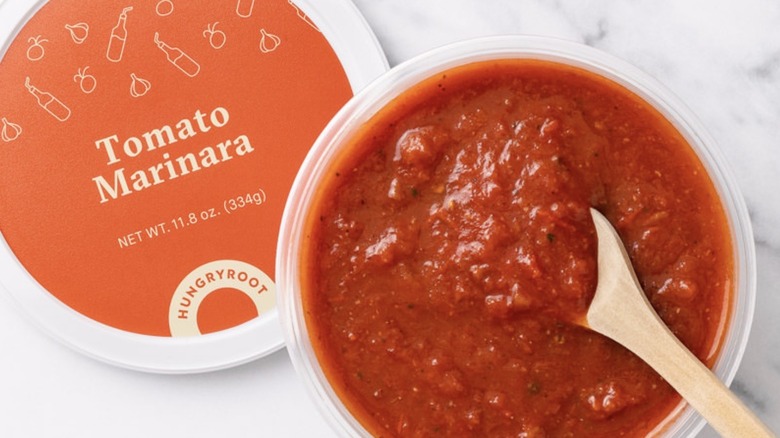 Open container of Hungryroot marinara with a wooden spoon resting in the sauce