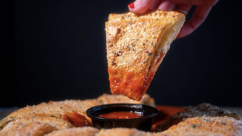 Piece of Mazzio's calzone ring dipped in sauce