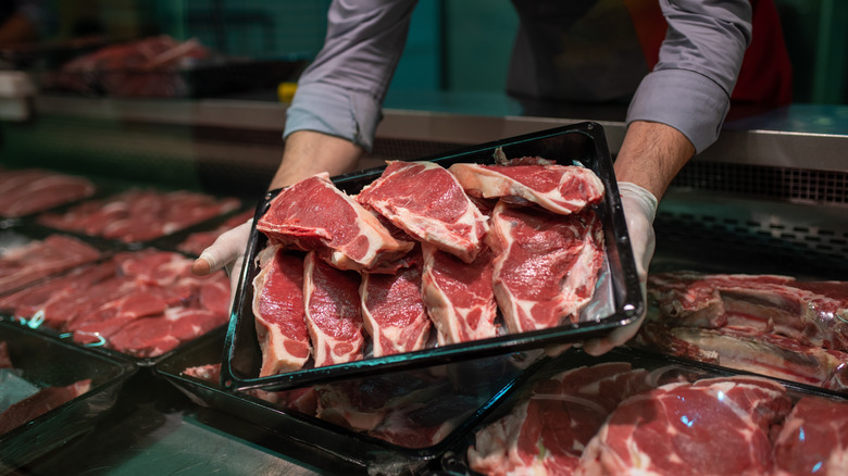 man holding a tray of raw beef