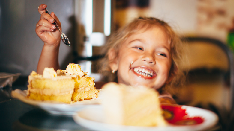 kid smiling and eating cake