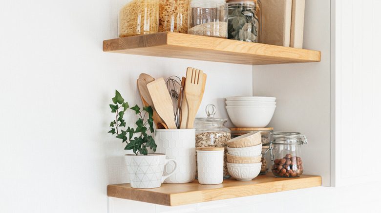 Small open shelves packed with dried goods, crockery, and mixing spoons