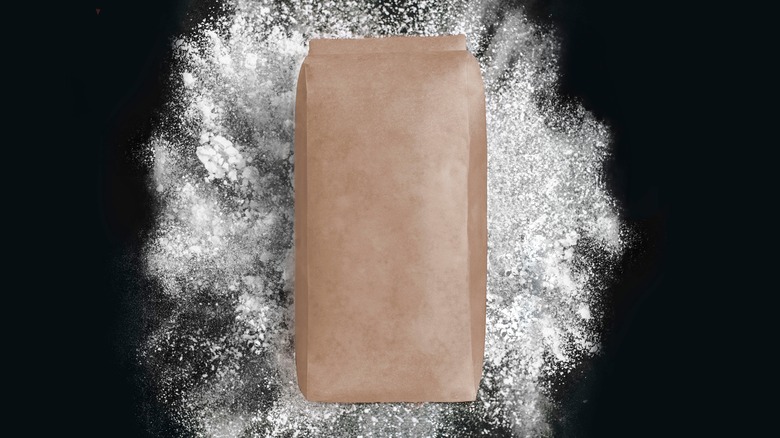 Bag of flour on black background with scattered flour underneath