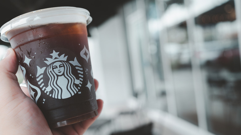A hand holds a to-go cup of Starbucks cold brew at a slight angle