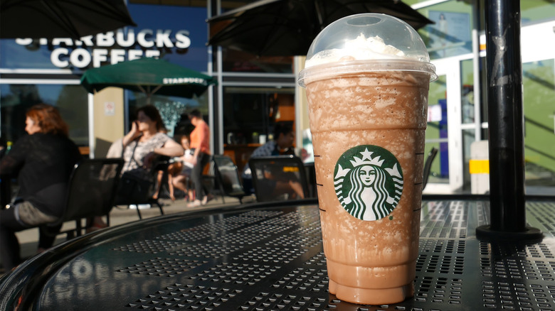 A venti Starbucks blended drink sits on an outdoor table