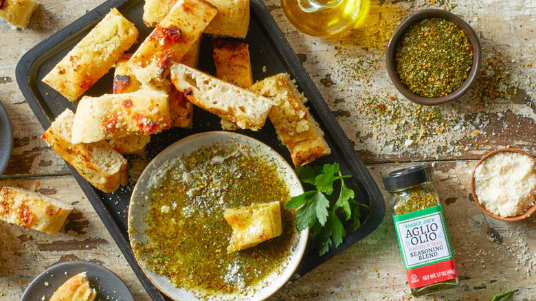 Jar of Trader Joe's Aglio Olio Seasoning Blend with plate of oil and sliced bread
