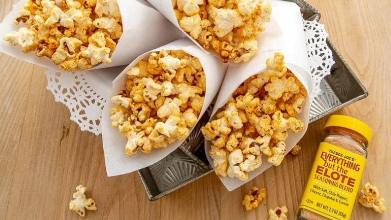 Jar of Trader Joe's Everything But The Elote Seasoning Blend with paper cones of popcorn