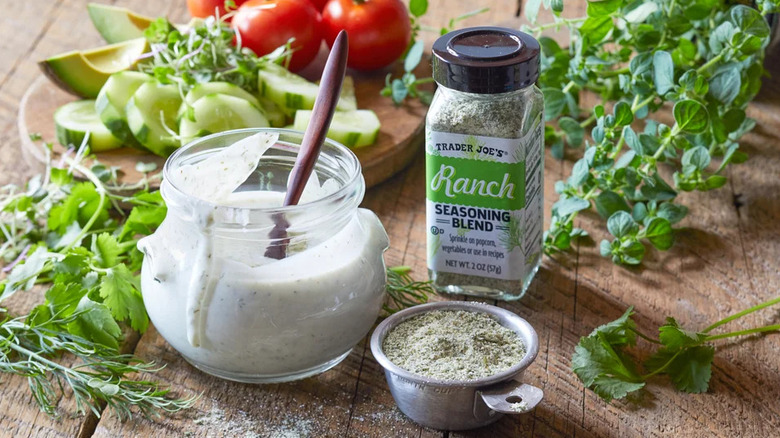 Jar of Trader Joe's Ranch Seasoning Blend with freshly made jar of ranch and fresh herbs and produce