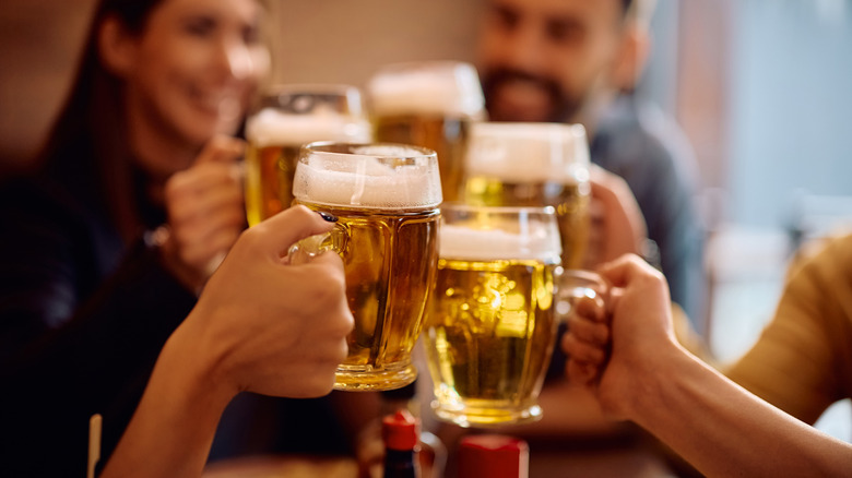 Several people clinking beer mugs