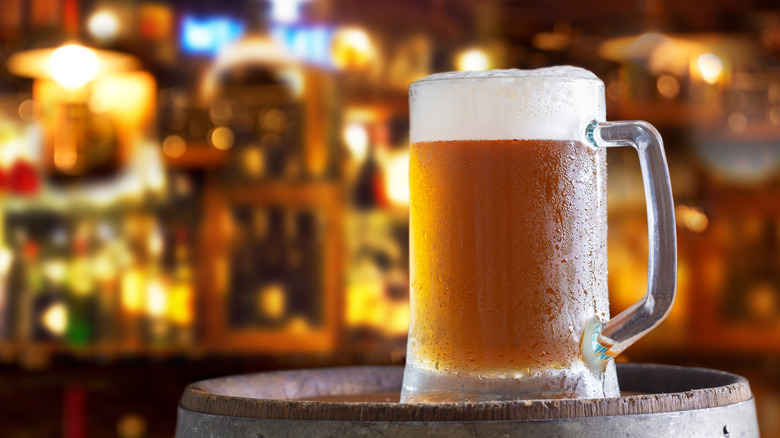 One beer with heavily frosted glass on a wooden barrel