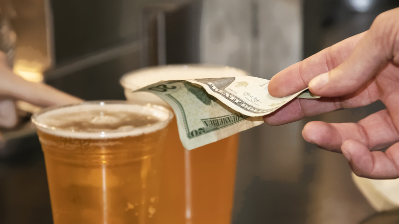 A person handing over a $20 bill for two beers