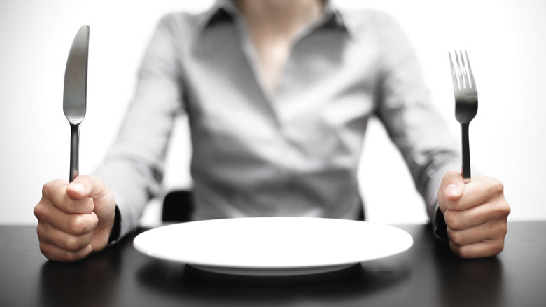 Woman holding silverware over an empty plate