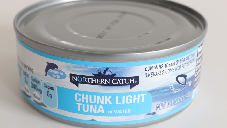 Six cans of Aldi Chunk Light tuna sit stacked on top of each other on a kitchen counter