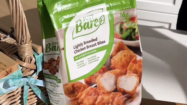 Bag of Just Bare Chicken Breast Bites sitting on a cutting board in a kitchen.