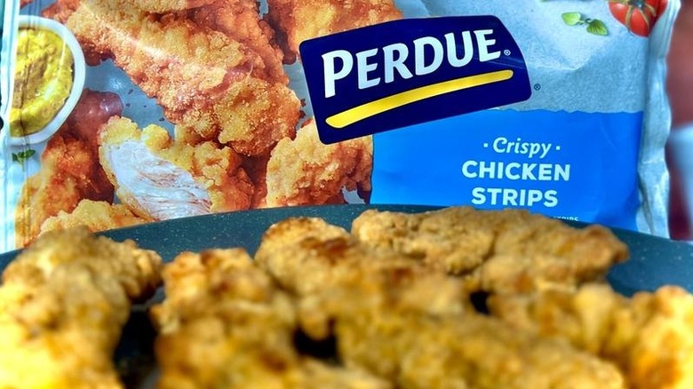 Bag of Perdue Frozen Breaded Crispy Chicken Strips behind plate of chicken strips