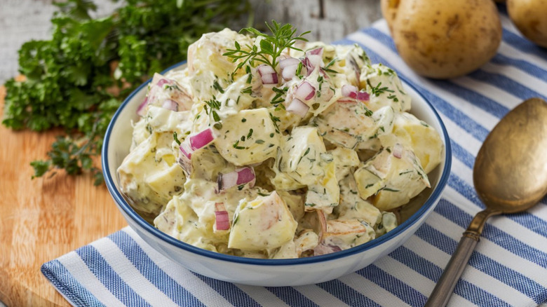 Creamy potato salad with diced onion in a bowl.
