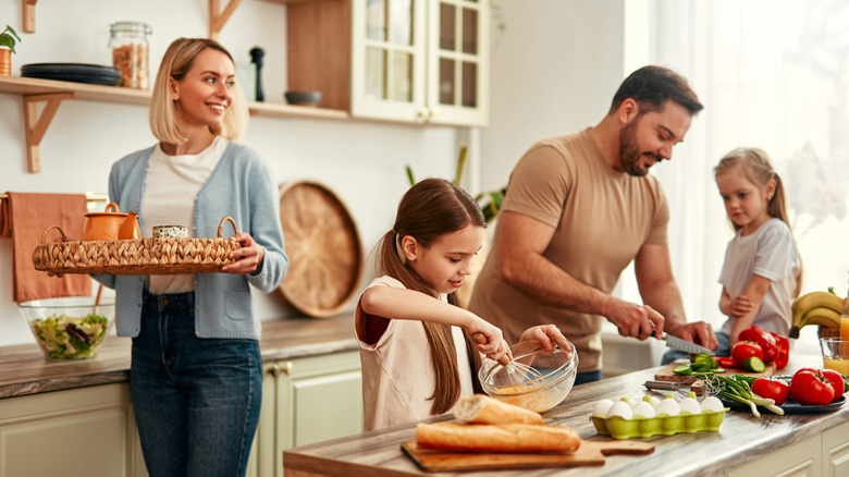 A family smiling and all working in a bright kitchen
