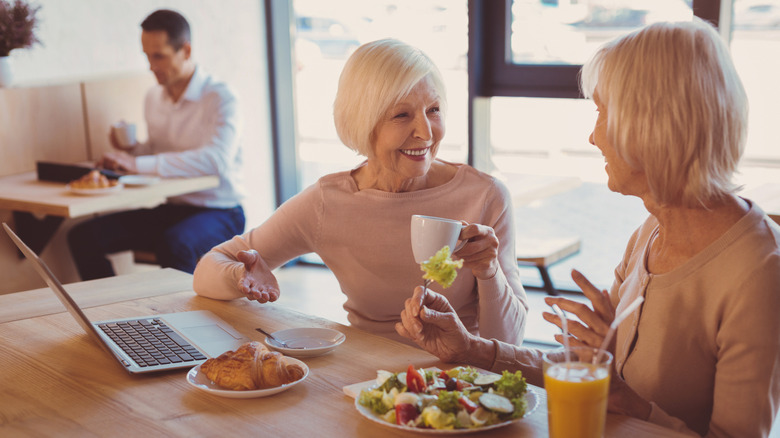 A group of senior citizens sit talking over coffee