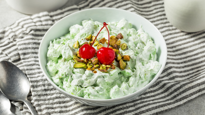 Watergate salad in bowl topped with cherries