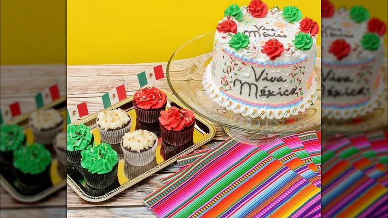 Cinco de Mayo themed colorful napkins next to cupcakes and a cake decorated in the colors of the Mexican flag