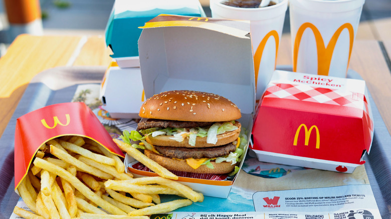 McDonald's fries and Big Mac on a serving tray with other food items in the background