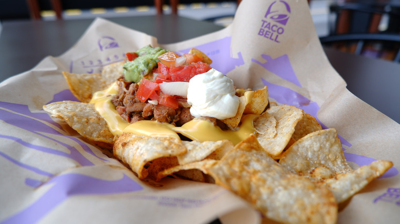 a taco supreme with cheese, sour cream, guacamole, and tomatoes
