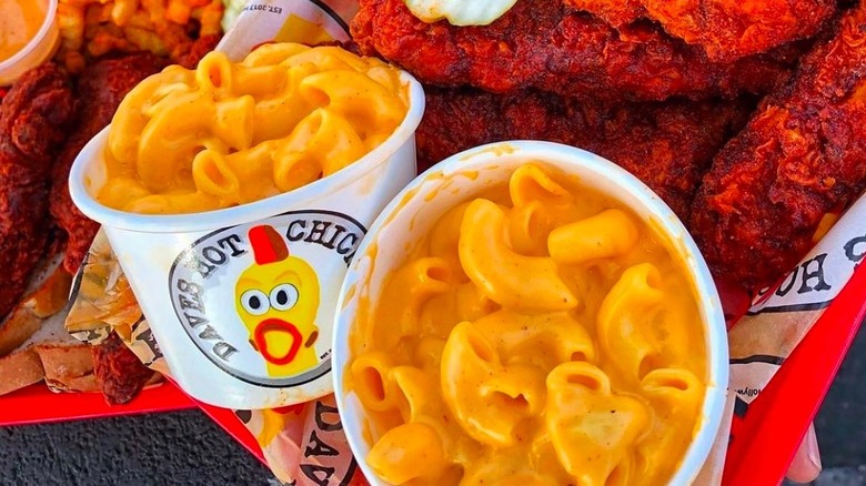bowls of dave's hot chicken mac and cheese surrounded by spicy chicken