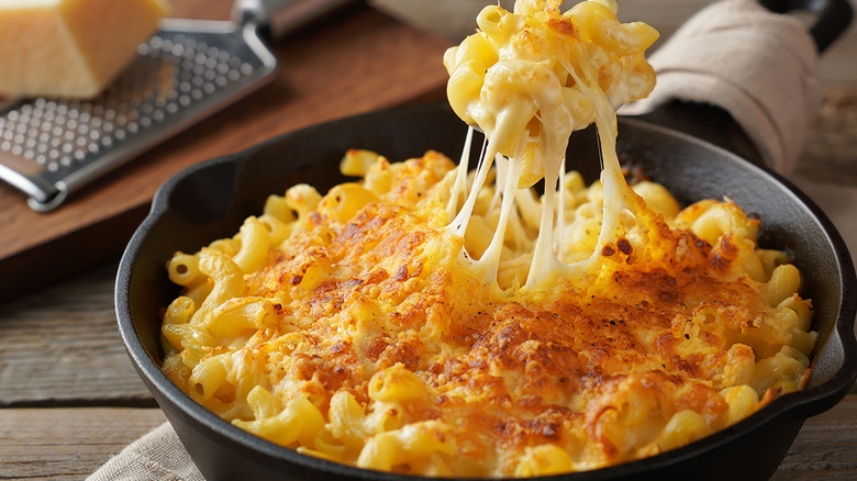 mac and cheese in cast iron skillet with cheese pull