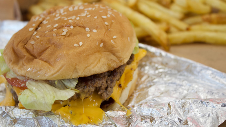 Five Guys burger on foil with fries in the background