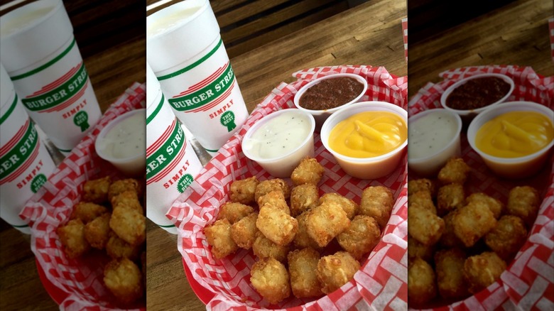 A fried chicken sandwich with tots sits on a white plate at Burger Street