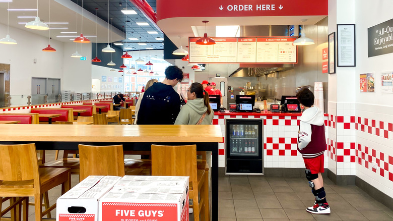A family of customers orders at the Five Guys counter