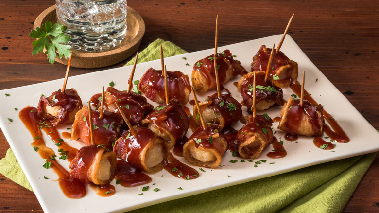 Bacon-wrapped water chestnuts coated in sauce on a plate.