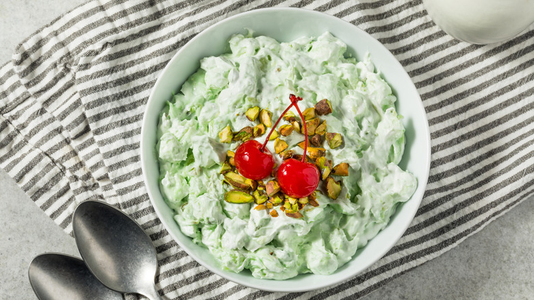 A bowl of fluffy, green, Watergate salad topped with pistachios and cherries