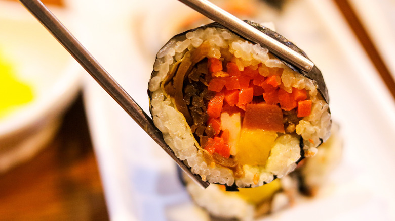 Chopsticks holding a piece of gimbap