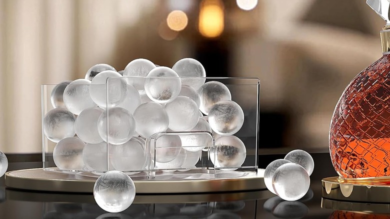 Crystal clear ice balls in a removable container sit next to a bottle of whiskey