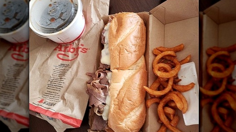 A French dip sandwich at Arby's next to curly fries and au just