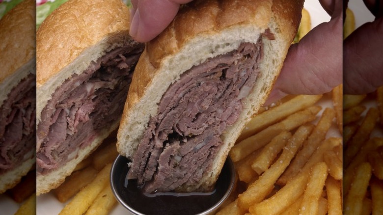 Closeup of a French dip sandwich being dunked in au jus