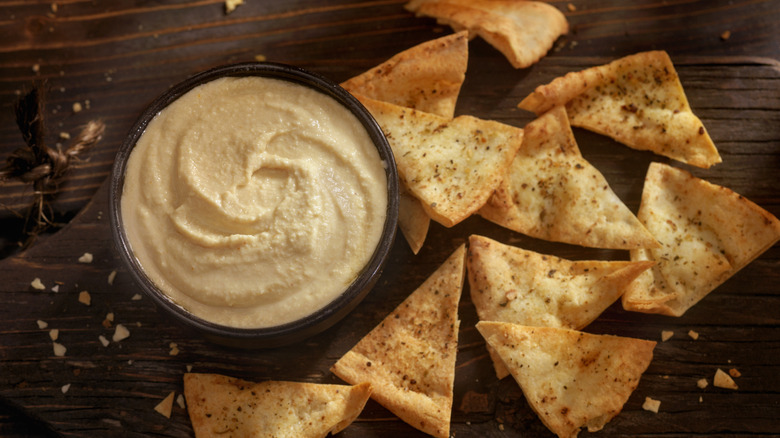 Bowl of hummus and pita chips on wooden table