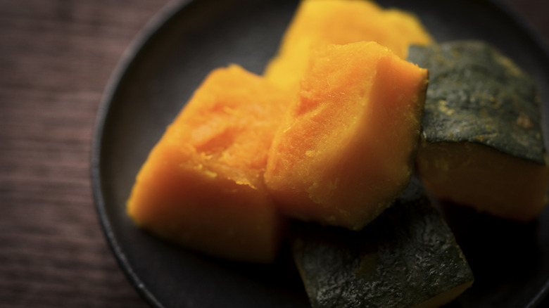Kabocha squash cut into chunks on a black plate