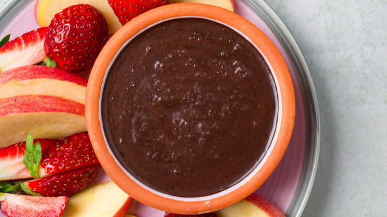 Chocolate hummus served with fruit in an orange bowl
