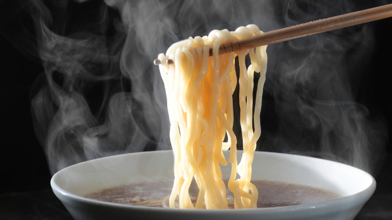 chopsticks pulling ramen noodles from soup
