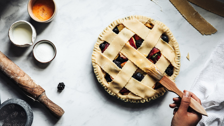 A fruit pie with a lattice crust being egg washed