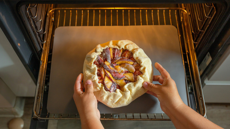 a galette in the oven with hands forming it
