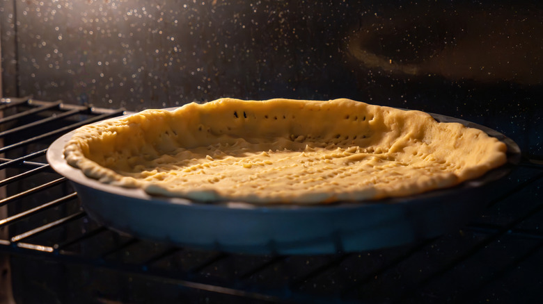 a docked pie crust baking in the oven